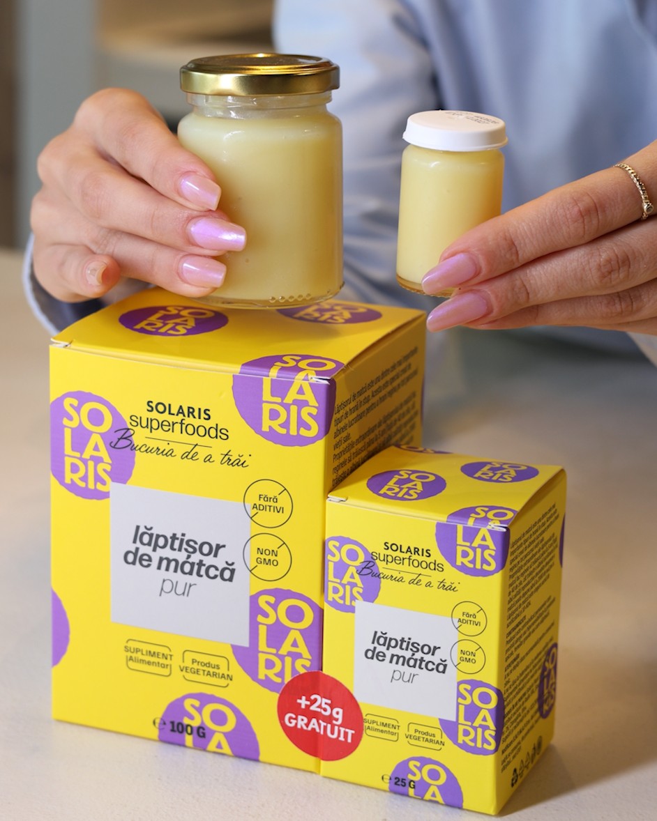 Borcanul de 100 g și borcănașul de 25 g de lăptișor de matcă, ținute deasupra cutiilor